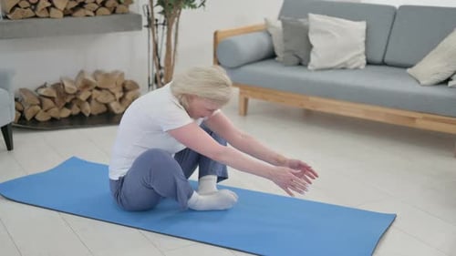 Senior Woman Stretching on Yoga Mat at Home