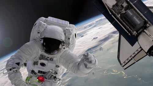 Felicidades desde el espacio. Astronauta con rosa roja y lanzadera con corazón