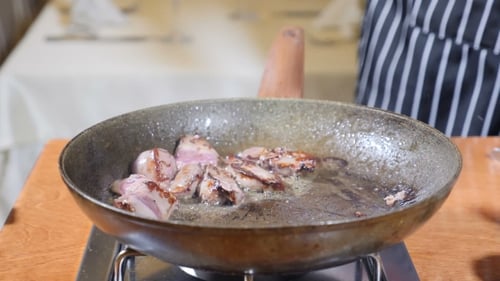 of Chef Cooking Flambe Style Dish with Slices of Liver on a Hot Frying Pan in Restaurant. .