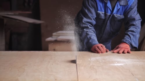 Worker Cuts Wood with Table Saw in Workshop