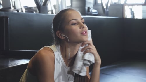 Bonne belle sportive souriante à la caméra essuyant la sueur de son cou à la salle de sport