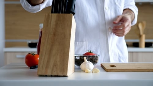 Chef in Modern Kitchen Sharpens Knife