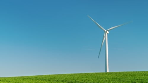 The Industrial Wind Generator Stands on a Green Hill. Against the Background of the Blue Sky