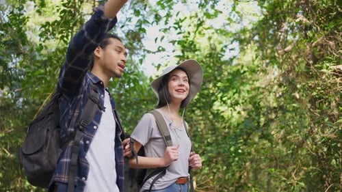 Asian young couple walk and travel in the forest, feel relax in nature wild, looking around the view