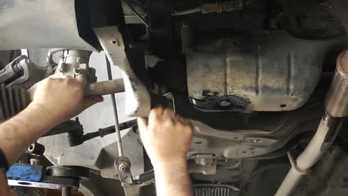 Car Mechanic Fixing Car Underneath in Garage