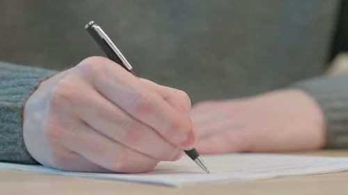 Close Up of Hands of Man Writing on Paper