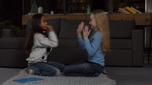 Two Young Girls Clapping Hands Sitting on Rug