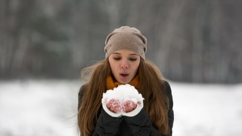 Woman Blowing Snow in a Winter Landscape