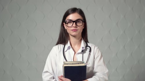 Smiling Woman Doctor Holds Books in Hospital