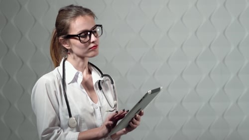Woman Doctor Uses Tablet in Exam Room