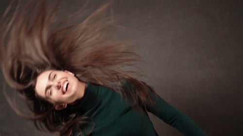 Smiling Woman Tossing Long Hair in Studio