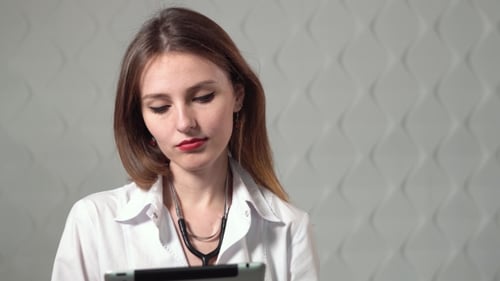 Young Woman Doctor Working on Tablet Indoors