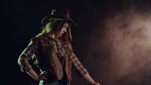 Cowgirl Takes Out a Revolver and Makes a Shot. Black Smoke Background. . Side View