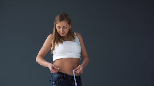 Mujer con sobrepeso que mide su cintura con una cinta métrica