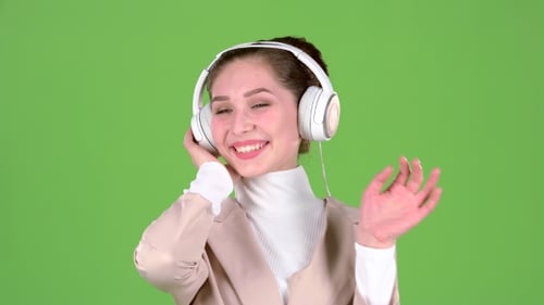Woman Listens To Melodious Songs in the Headphones. Green Screen