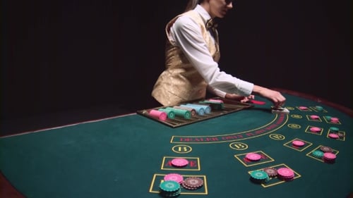 Casino Croupier Girl Distributes Cards on the Poker Table Top Using Cut Card. Black Background.