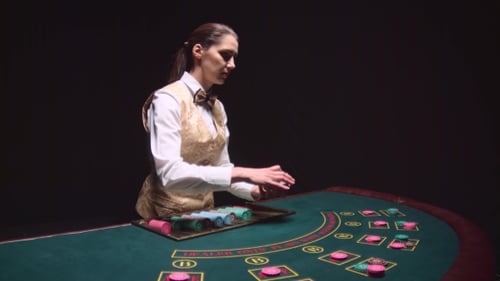 Casino Croupier Girl Distributes Cards on the Poker Table Top. Black Background.