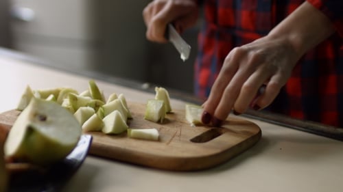 Woman Slicing Apple into Chunks on Cutting Board