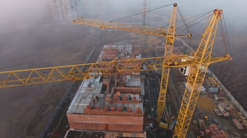 Construction Site in the Fog with a Bird's Eye with Tower Cranes on the Sunset