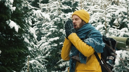Man in Yellow Winter Jacket Cleans His Hands From Snow Standing in the Mountain Forest
