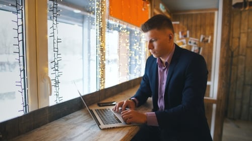 Confident Young Man in Casual Wear Working on Laptop While Sitting Near Window in Creative Office or