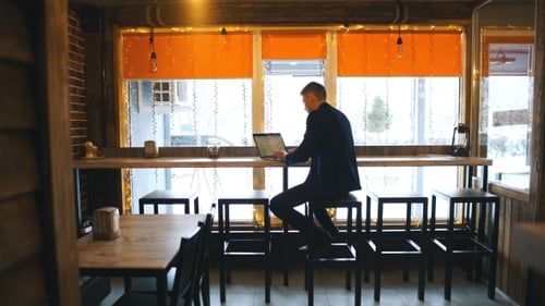 Working From Cafe. Cheerful Young Man in Smart Casual Wear Looking at Laptop and Sitting Near Window