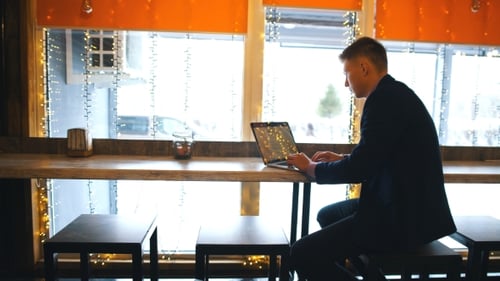 Working From Cafe. Cheerful Young Man in Smart Casual Wear Looking at Laptop and Sitting Near Window