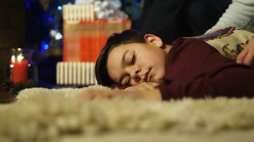 Child Sleeping on Rug Before Christmas Tree