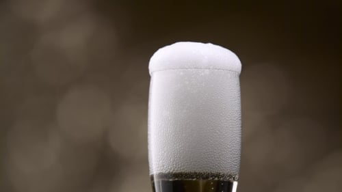 Champagne Poured Into Glass From Green Bottle. Bokeh Background.