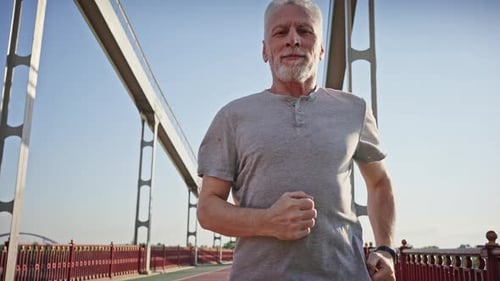 Active Senior Man Running on Bridge in Sunlight