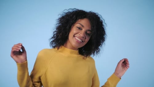 Woman Smiling and Dancing on Blue Background