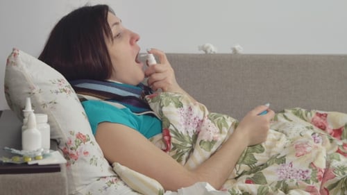 Femme malade couchée dans son lit à la maison, mal de gorge