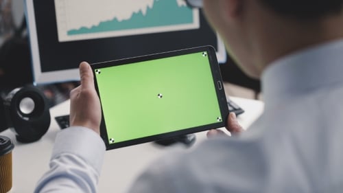 A Man Using a Tablet PC with a Green Screen in Front of Camera.