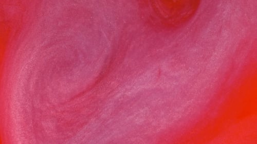 Réaction d'encre rouge dans l'eau créant un arrière-plan abstrait.