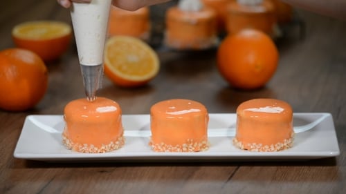 Décorez des mini gâteaux à l'orange avec de la crème