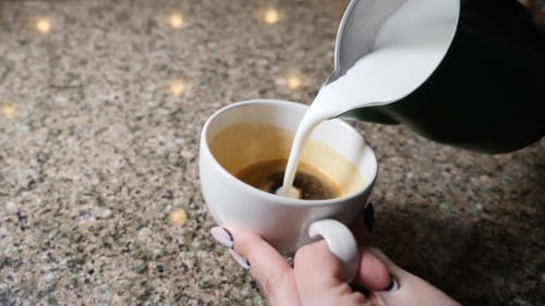 Pouring Creamy Milk Into a Mug of Coffee
