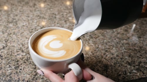 Foamy Milk Being Poured Into Coffee Cup