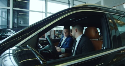 Salesman Giving Key To Buyer Inside New Car