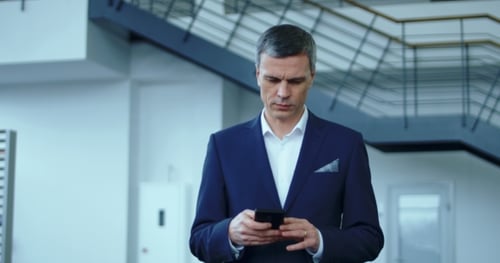 Businessman Using Smartphone in Modern Office Lobby