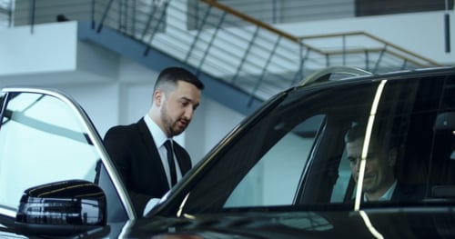 Salesman Presenting Car in Showroom