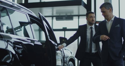 Man Inspecting Car with Salesman at Dealership