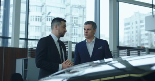 Men Talking in Car Dealership Next to Car