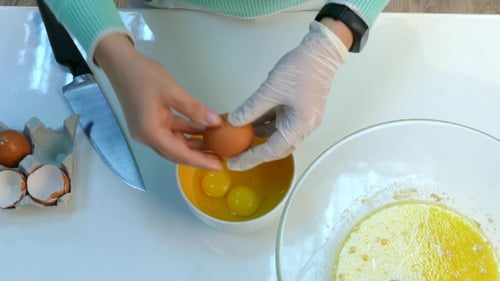 Cracking Fresh Eggs Into Yellow Mixing Bowl