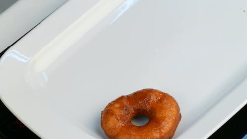 Golden Donuts being Placed on Serving Platter