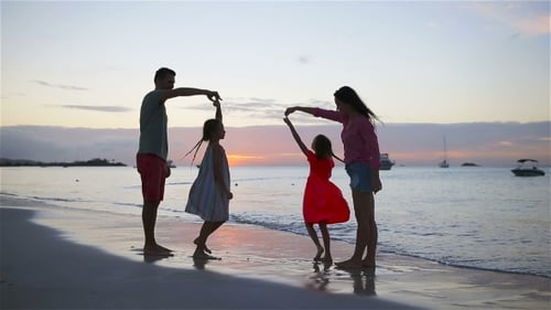 Parents and Two Kids Have a Lot of Fun on the Beach at Sunset. Family of Four in Love, Happy