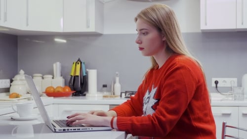 Woman Typing on Laptop in Bright Kitchen