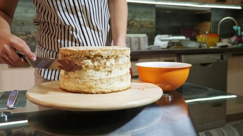 Woman Frosting Layered Cake in Kitchen