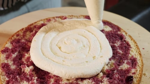 of Putting Cream on a Sponge Cake. Cake on a Rotating Stand