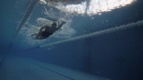 Femme nageant Crawl Stroke dans l'eau bleue Piscine flottante Vue sous-marine