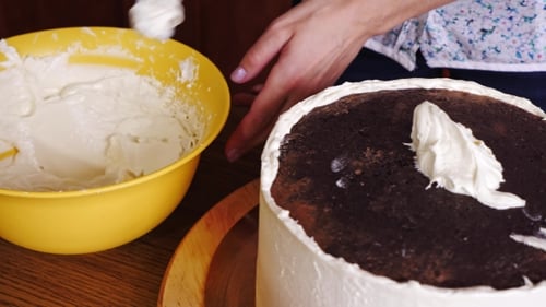 Woman Frosting Chocolate Cake With Creamy White Icing
